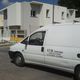 Furgone bianco con iscrizione "A.T.M. Costruzioni" davanti a edifici in costruzione.