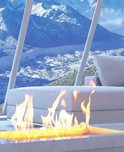 Modernes Wohnzimmer mit Kamin, Panoramablick auf verschneite Berge durch große Fenster.