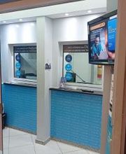 Agência de câmbio com balcões de atendimento e tela de publicidade na parede.