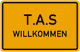 Gelbes Schild mit der Aufschrift "T.A.S WILLKOMMEN" in schwarzer Schrift.