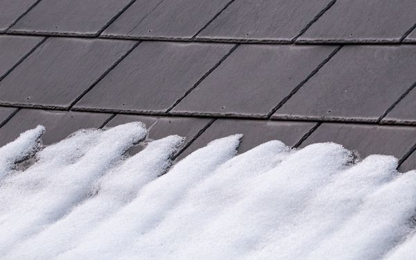 Ein Schieferdach in Nahaufnahme bedeckt mit Schnee.