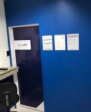 Parede azul com placa "SALA VIP", janela de atendimento e cadeira preta em um ambiente interno.