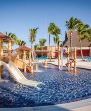 Piscina con tobogán y palmeras en un complejo turístico bajo un cielo despejado.