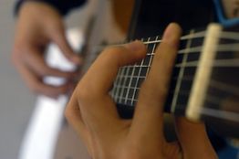Nahaufnahme von Händen, die Gitarre spielen.