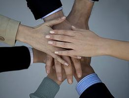 Multiple hands stacked together, symbolizing teamwork and unity.