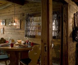 Gemütliches Holzinterieur eines Restaurants mit gedecktem Tisch und dekorativer Beleuchtung.