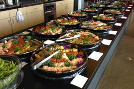Buffet table with assorted seafood platters and tongs, ready for serving.