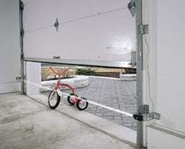 Garage door blocked by a tricycle, preventing it from closing fully.