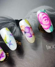 Arte de uñas con diseños florales coloridos y detalles precisos sobre fondo oscuro.