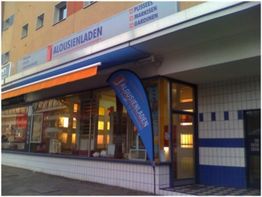 Außenansicht eines Geschäfts mit dem Schild "Jalousienladen" und blauer Fahne vor dem Eingang.