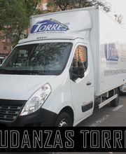 Camión blanco de mudanzas en una calle, con el texto "Mudanzas Torres" al frente.