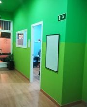 Pasillo interior con paredes verdes, una puerta y un cartel de salida de emergencia.