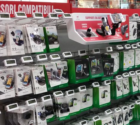 Scaffale di accessori per cellulari in un negozio, tra cui supporti per auto e cavi.