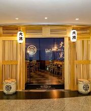 Fachada de un restaurante japonés con puerta de madera y menús exhibidos en la entrada.