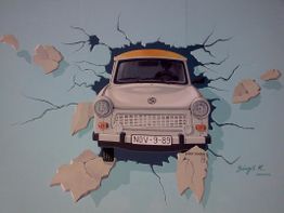 Ein Auto durchbricht eine Wand mit Rissen, Nummernschild "NOV-9-89".