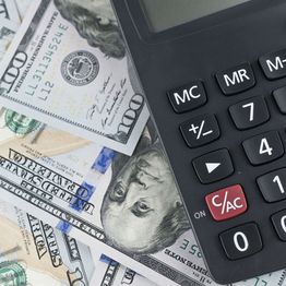 Calculator on U.S. hundred-dollar bills, symbolizing finance and budgeting.