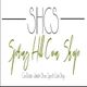 "Logo for Spring Hill Coin Shop, featuring text in cursive and a description of shop offerings."