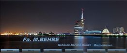 Bremerhaven Skyline bei Nacht mit Schrift "Fa. M. BEHRE, Gebäude-Service Deluxe Bremerhaven" im Vordergrund.