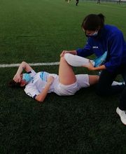 Jugador en el suelo recibe asistencia en la pierna por parte del personal médico en el campo.