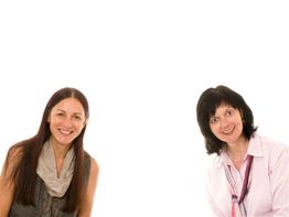 Zwei lächelnde Frauen vor weißem Hintergrund, eine mit langen und eine mit kurzen Haaren.