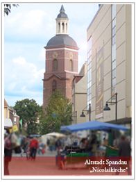 Alter Kirchturm in Spandau mit geschäftiger Straße im Vordergrund.