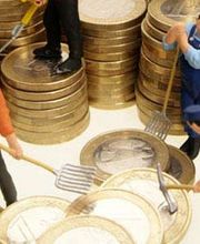 Miniaturfiguren arbeiten mit Harken auf Münzstapeln, symbolisieren Finanzen und Arbeit.