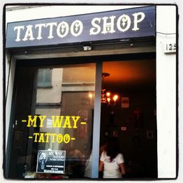 Ingresso del "Tattoo Shop - My Way", con insegna e interni illuminati visibili.