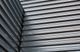 Corrugated metal wall with intersecting lines creating an industrial pattern.