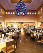 Restaurante amplio y colorido con mesas arregladas, luces colgantes y techo alto.