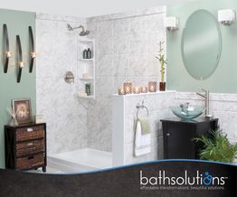 Modern bathroom with white tiles, vanity, mirror, and decor, showcasing Bath Solutions logo.