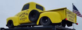 Yellow vintage truck with "Waterloo Auto Service" on the side, parked on a platform.