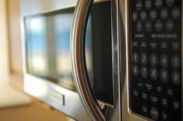 Close-up of a microwave oven with a stainless steel handle and visible control panel.