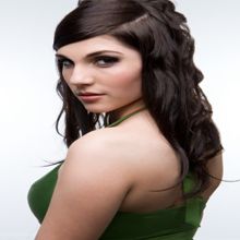 Woman with long dark hair in a green top, looking over her shoulder.