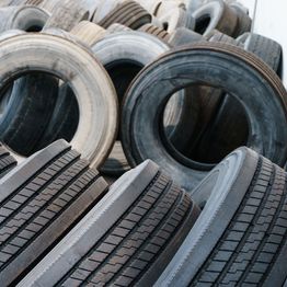 Stacked used tires in various conditions and colors, arranged diagonally.