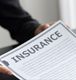 Person holding an insurance document with blurred text.