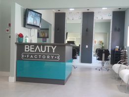 Recepção de salão de beleza moderno, com balcão azul e cadeiras de cabeleireiro em preto e branco.