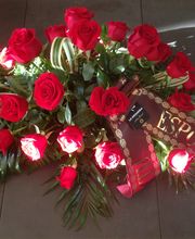 Arreglo de rosas rojas con cinta que dice "ESPOSO", rodeado de hojas verdes.