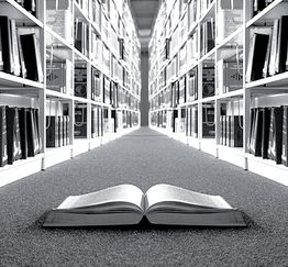 Offenes Buch auf dem Boden zwischen Bücherregalen in einer Bibliothek, schwarz-weiß.