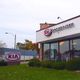 Kia dealership building with signs and green lawn in the foreground.