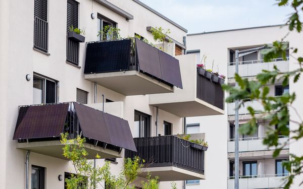 Balkone an der Fassade eines Wohnhauses. Zwei von ihnen haben jeweils ein Balkonkraftwerk am Geländer montiert.