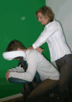 Eine Person erhält eine Massage auf einem speziellen Stuhl vor einem grünen Hintergrund.