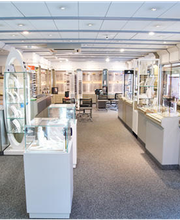 Ein heller Optikerladen mit weißen Regalen und beleuchteten Vitrinen, die Brillen präsentieren.