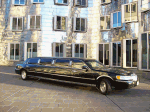 Schwarze Limousine vor modernem Gebäude mit vielen Fenstern.