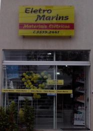 Fachada da loja Eletro Marins com balões amarelos e verdes na vitrine.