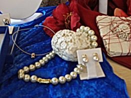 Perlenhalskette und Ohrringe auf blauem Stoff, verziert mit weißer Koralle und rotem Tuch.