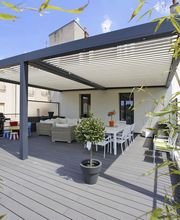 Moderne Terrassenpergola mit Sitzbereich und Pflanzen in Töpfen, umgeben von Bambus.