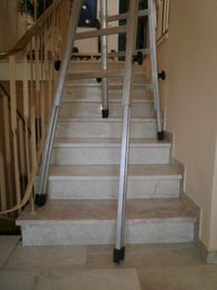 Leiter auf einer Treppe, umgeben von einem Geländer.