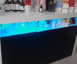 Estante de productos de belleza con iluminación azul y jarrón con flores secas encima.