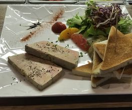 Ein Teller mit Foie Gras, Toast, Salat, Orangen, Erdbeeren und Balsamico-Dekoration.