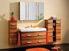 Holz-Badezimmerschrank mit Spiegel, Waschbecken, Kaktus und roten Handtüchern.